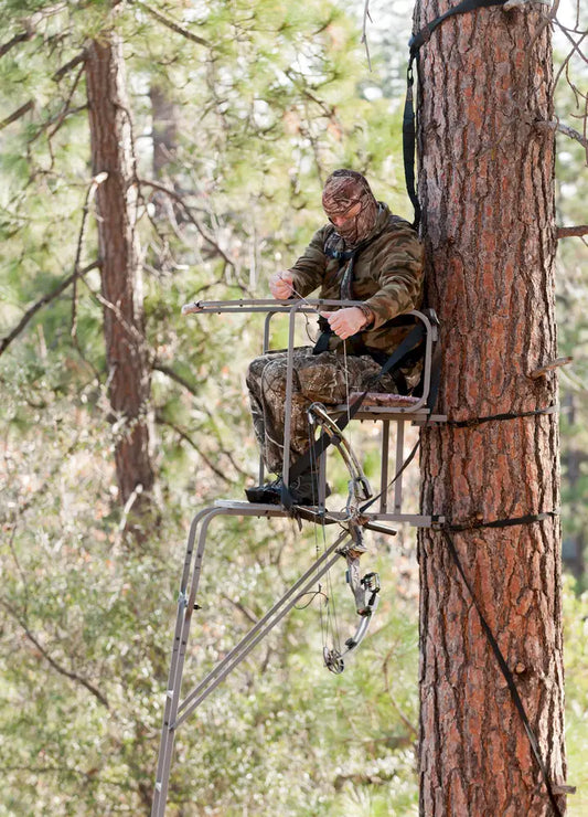 Man in camo outfit hunts for deer in a tree stand